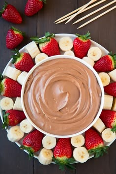 a chocolate dip surrounded by sliced bananas and strawberries