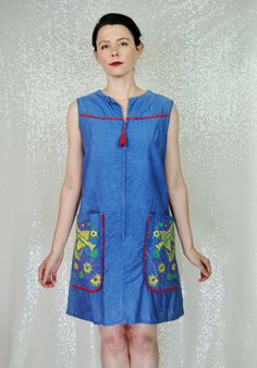 Super fun and unique vintage sheath style house dress. The item is a blue chambray-like fabric. It zips up the front with metal zipper and features really large pockets. The best part of this piece are the watering cans on the pockets- a very unique print and great for your favorite gardener! There is no label or size tag. It is meant to be a loose comfy fit and as such would likely best fit a modern Small or possibly a Medium. There is no give to the fabric! Model is modern size 4/6 and dress f Fitted Vintage Blue Denim Dress, Fitted Blue Vintage Denim Dress, Retro Blue Denim Dress With Pockets, Vintage Blue Sleeveless Denim Dress, Vintage Blue Denim Dress With Pockets, Vintage Blue Dresses With Pockets, Blue Vintage Dresses With Pockets, Vintage Blue Denim Dress For Summer, Retro Denim Dress With Pockets