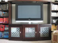 a flat screen tv sitting on top of a wooden entertainment center next to a book shelf