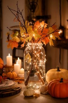 a table with candles, pumpkins and other fall decorations on it in a mason jar