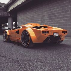 an orange sports car parked in front of a building