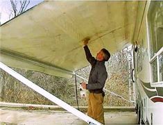 a man is painting the side of a bus with a white paint job on it