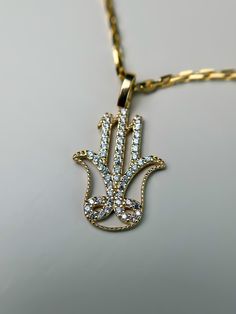 This stunning 14k solid gold Fatima Hand pendant, also known as the Hamsa, is beautifully adorned with sparkling cubic zirconia stones. A symbol of protection, peace, and blessings, the intricate detailing of this pendant makes it both meaningful and stylish. The shimmering cubic zirconia adds just the right amount of brilliance, making it perfect for everyday wear or special occasions. P R O D U C T ∙ M E A S U R E M E N T S * 100% 14k Solid Gold * Length:20 mm /  0.80 inch *Height: 14.5mm / 0. Gold Jewelry With Diamond Accents, Gold Diamond Necklace With Intricate Design, Intricate Yellow Gold Diamond Necklace Gift, Spiritual Gold Necklaces With Hand-set Details, Spiritual Gold Necklaces With Hand Set Details, Spiritual Hand Set Gold Necklaces, Gold Diamond Necklace With Pave Setting As Gift, Symbolic Diamond Wedding Jewelry, Gold Diamond Necklace With Intricate Design For Anniversary