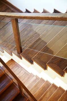 a wooden stair case with glass railing and handrail