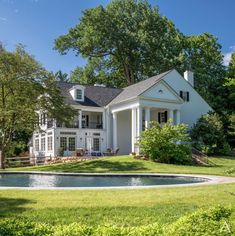 a large white house sitting on top of a lush green field next to a pool