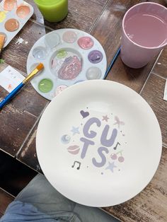 a plate with the word g u s painted on it next to paintbrushes and other crafting supplies