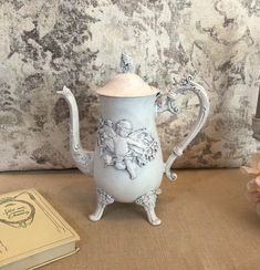 an antique teapot and book on a table