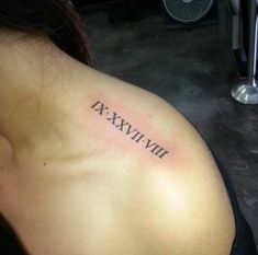 the back of a woman's shoulder with roman numerals tattooed on it