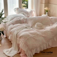 there is a bed with pink sheets and white pillows on the floor next to a window