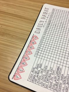 a close up of a notebook on a wooden table with writing and numbers in it