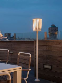 an outdoor table with chairs and a lamp on it