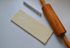 a piece of cheese next to a rolling pin on a white counter top with a name tag