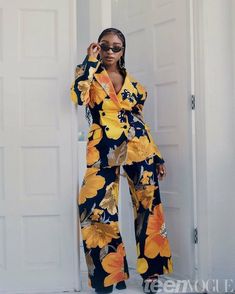 a woman standing in front of a white door wearing a yellow and black floral suit