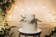 a white wedding cake sitting on top of a table next to flowers and greenery