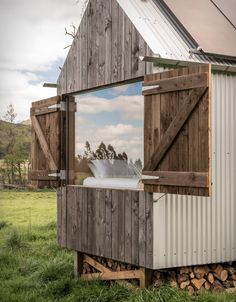 an outhouse with a barn door and window that is open to let in light