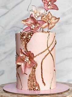 a pink and gold cake with flowers on top