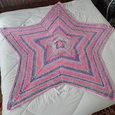 a crocheted pink and purple star on a bed