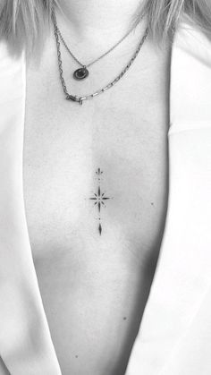 a black and white photo of a woman's chest with a cross tattoo on it