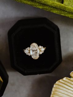 an engagement ring sits in a velvet box on the floor next to other jewelry items