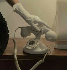 a person in white gloves is using an old phone