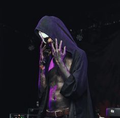 a man with purple paint on his face and hands, standing in front of a stage