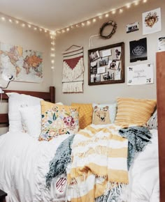 an unmade bed with blankets, pillows and pictures on the wall above it in a dorm room