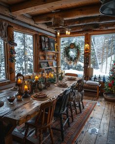 a dining room table with candles and christmas wreaths on the window sill in front of it