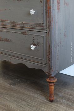 an old dresser with rusted paint on it's drawers and wood flooring