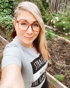 a woman wearing glasses taking a selfie in the garden