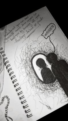 an open notebook with a drawing of two people in a nest on top of it