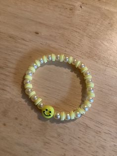 a yellow smiley face beaded bracelet on a wooden table