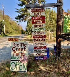 a bunch of signs that are on the side of the road in front of a fence