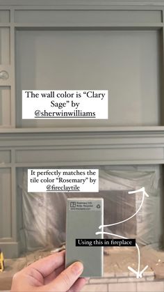 a person holding up a cell phone in front of a fireplace with the text, the wall color is gray sage by @ sherylnvilllams