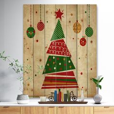 a christmas tree with ornaments hanging from it's sides in front of a wooden wall