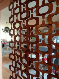 a large wooden mirror hanging on the side of a wall next to a table and chairs