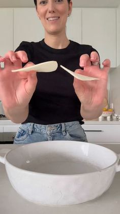 a woman holding two spoons in front of a bowl