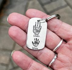 a person is holding a dog tag that says queen and baby handprints on it