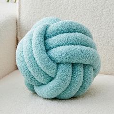 a blue knoted pillow sitting on top of a white couch