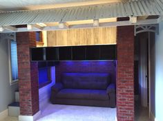 an empty living room with a couch in the middle and blue lights on the ceiling