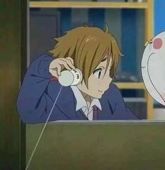 an anime character talking on the phone with another person in the background looking at him