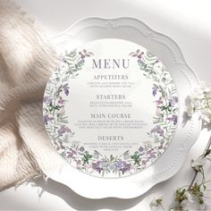 a white plate topped with a menu on top of a table next to some flowers