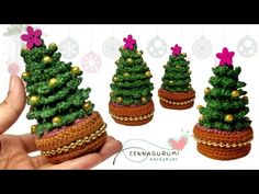 small crocheted christmas trees are being held by someone's hand in front of them