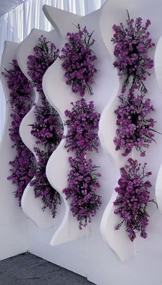 purple flowers are growing on the side of a white wall