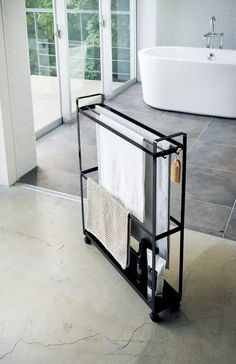 a bathroom with a bathtub, sink and towel rack on the floor in front of it