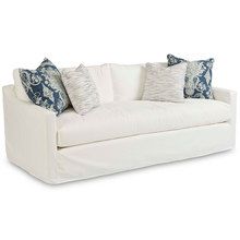 a white couch with pillows on it and some blue and white throw pillows in the back