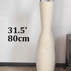 a tall white vase sitting on top of a carpeted floor