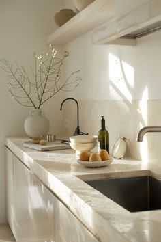 a bowl of fruit sitting on top of a kitchen counter next to a sink and faucet