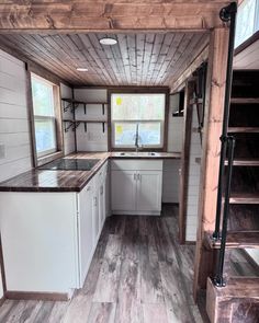 the interior of a tiny house with wood flooring and white cabinets, stairs leading up to an open kitchen area