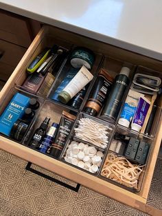 an open drawer with various items in it on top of a carpeted floor next to a table