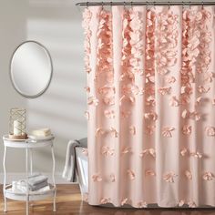 a shower curtain with pink flowers on it in a white and gray bathroom, next to a round mirror